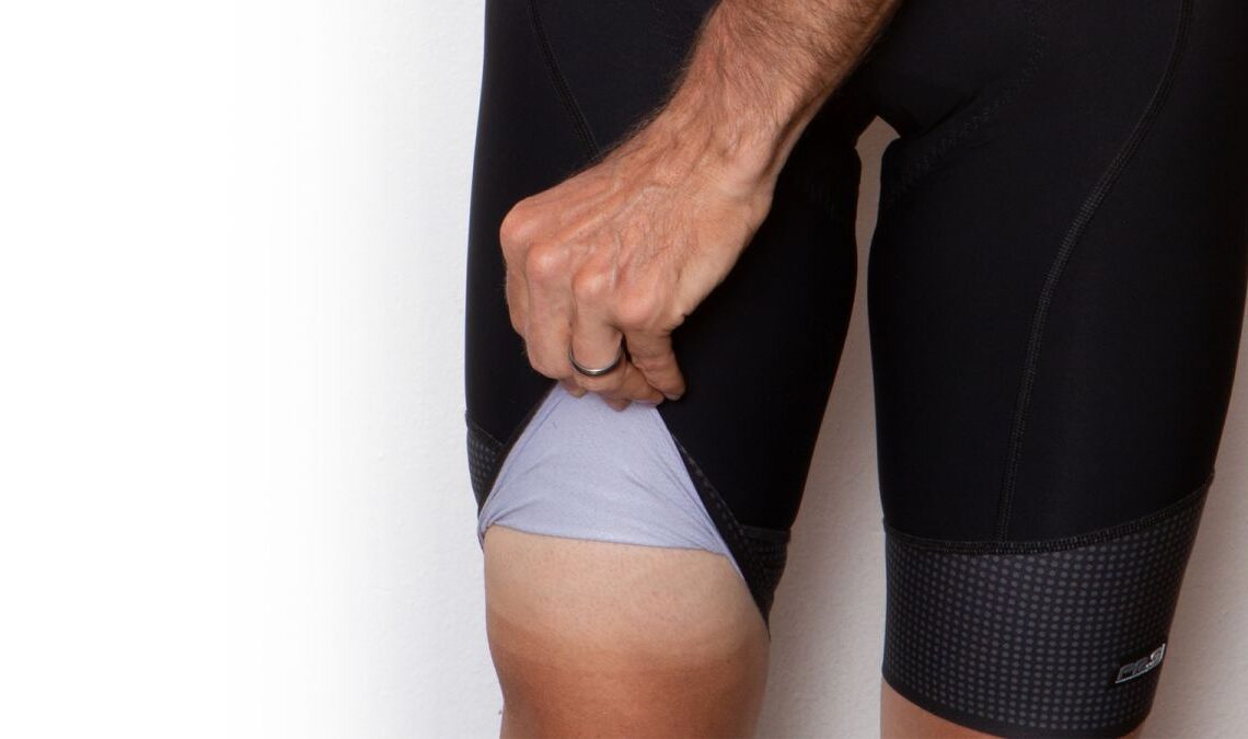 Our cycling shorts product tester lifts the leg of his bib shorts to reveal a strong tan line