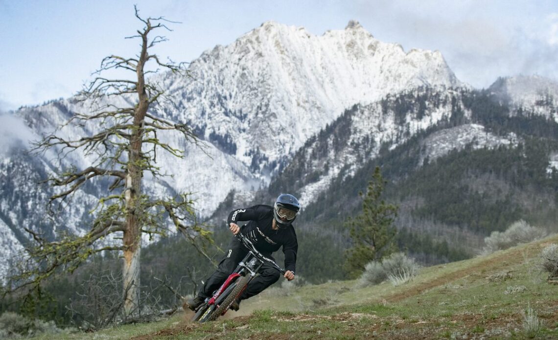 Elliot Jamieson corners his mountain bike below a snow-covered mountian peak