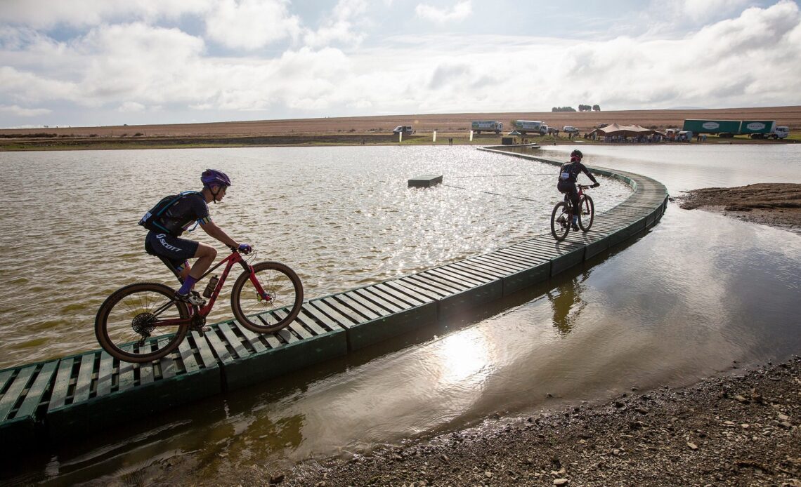 Cape Epic 2023 riders ride through a winnery on a raised walkway