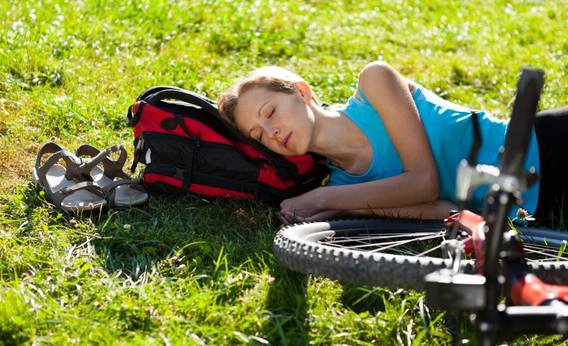 Young cyclist enjoying sleeps relax lying in the fresh grass