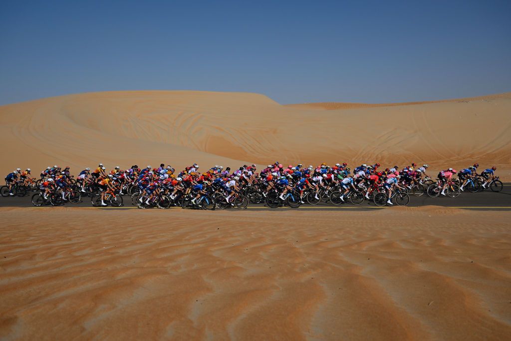 A general view of the peloton passing through a landscape in the desert during the UAE Tour Women on stage 2 a 113km stage Al Mirfa Bab Al Nojoum to Madinat Zayed