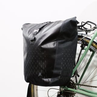 A black pannier with reflective details mounted to a green bike against a white background