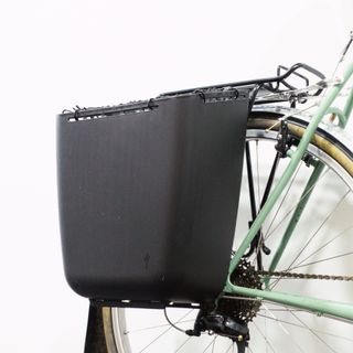 A black tub pannier mounted to a green bike against a white background