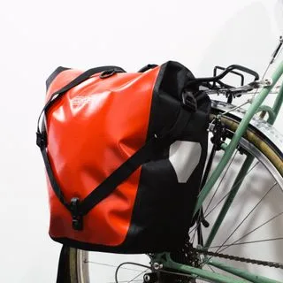 A bright red pannier mounted to a green bike against a white background