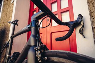 a close up of the front-end of a Colnago c68 rim brake bike, which stands in front of a red door