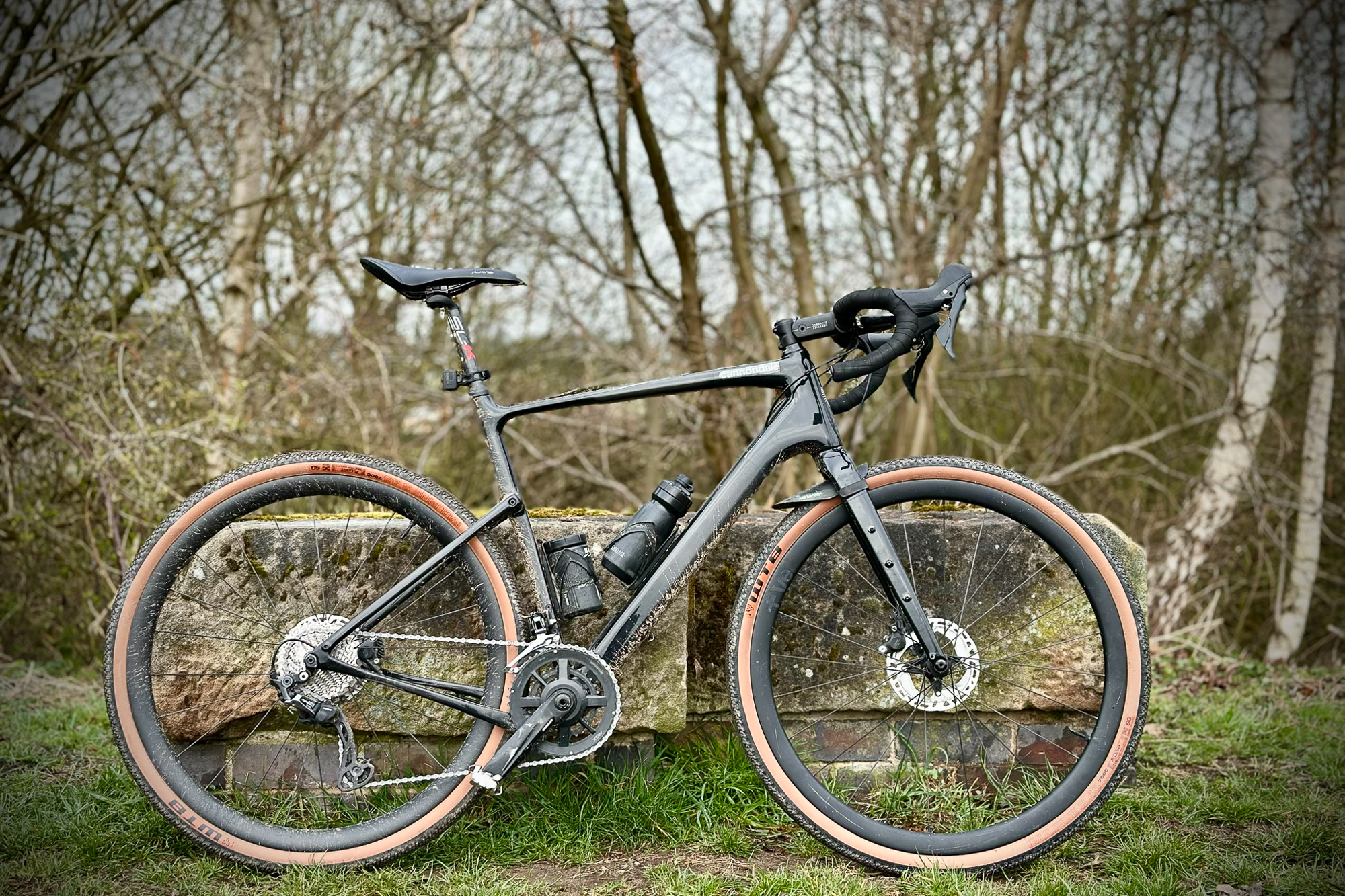 Black Cannondale Topstone bike with tan wall tyres leaning on a gritstone block