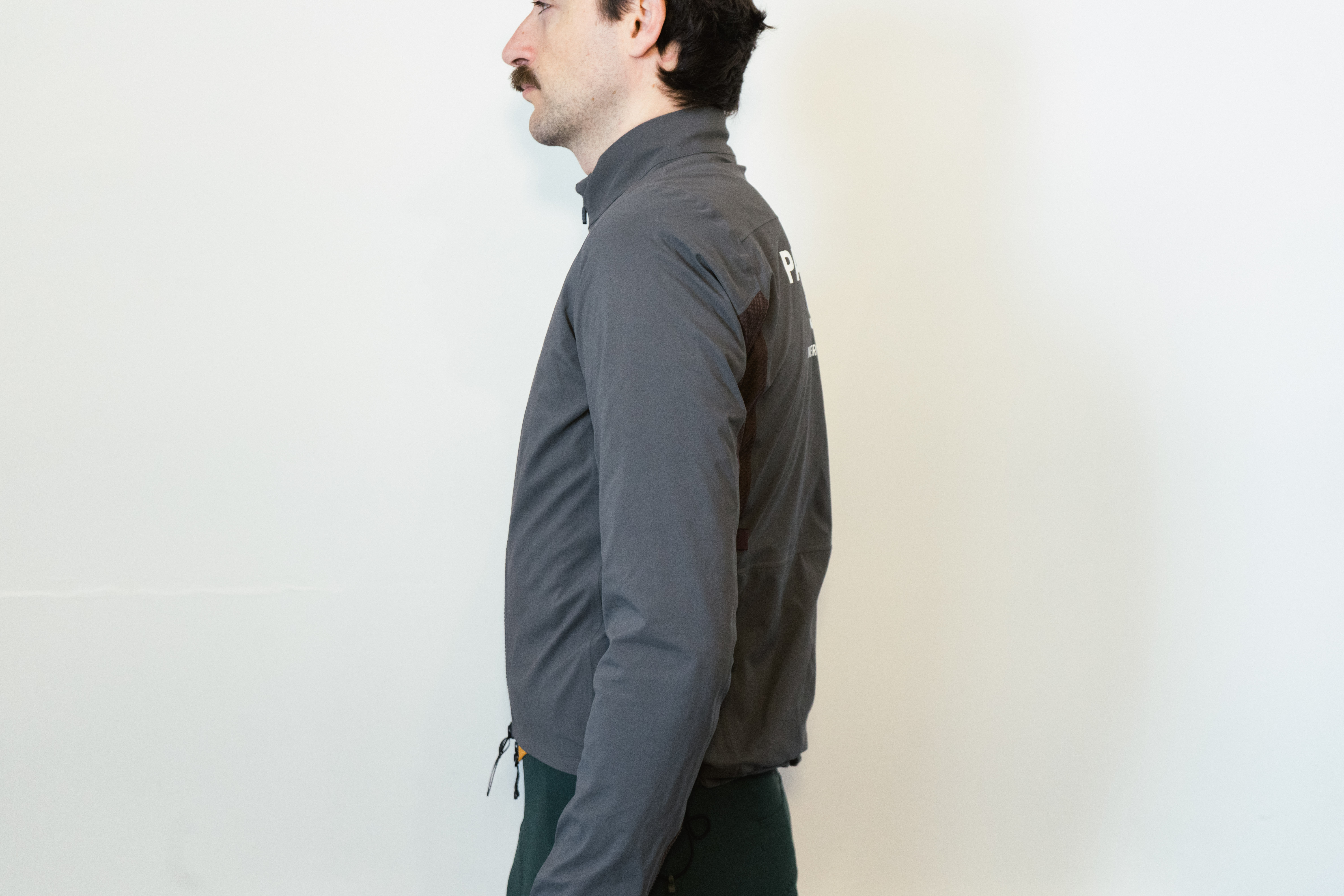 A man in a grey waterproof jacket against a white wall