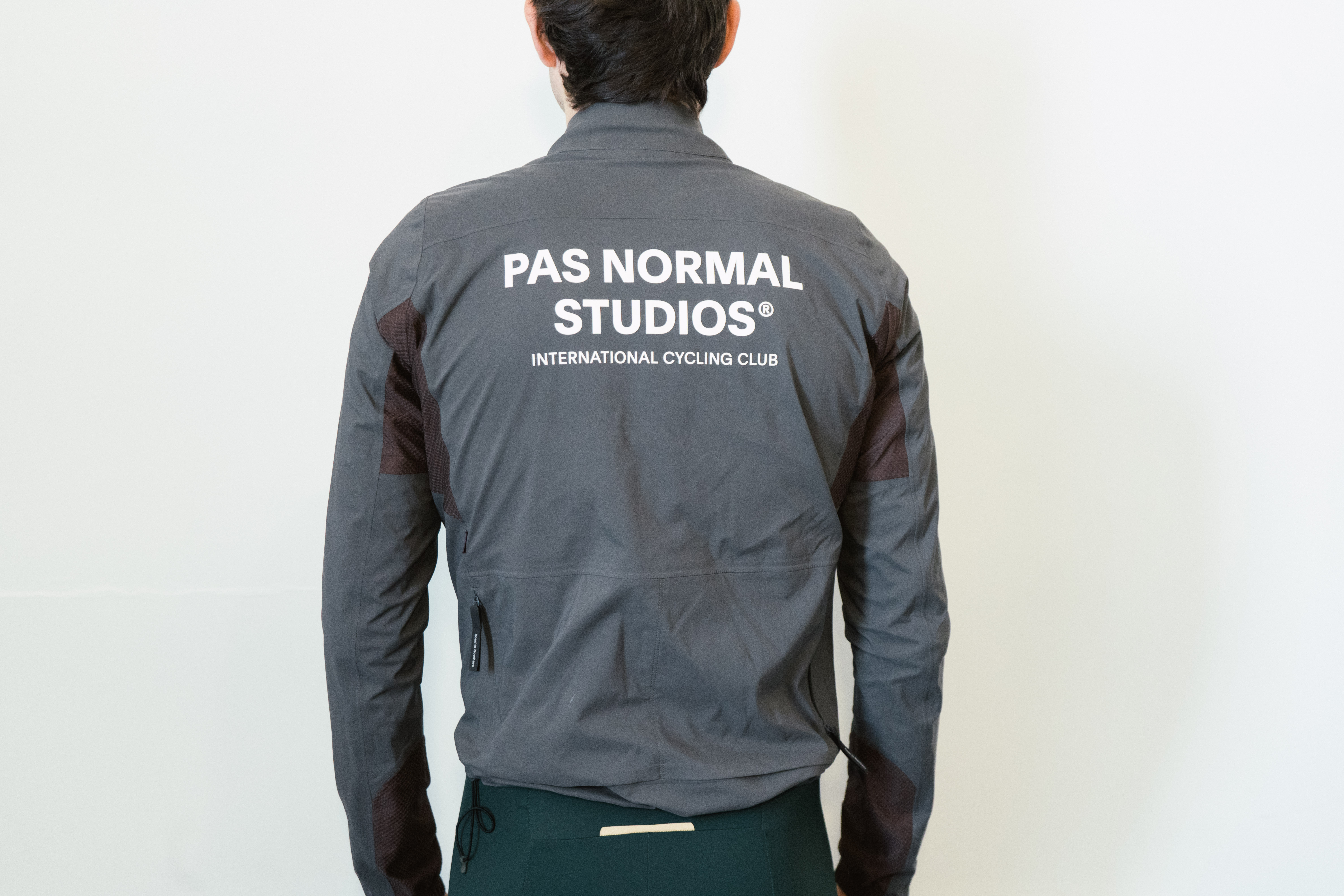 A man in a grey waterproof jacket against a white wall